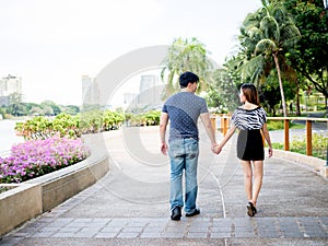 Asian couple holding hands walking in the park