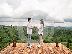 Asian couple holding hands on wooden balcony with mountain view. Mariage proposal concept. terrace for camping tent with landscape photo