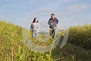 Asian couple jogging together, outdoor morning run in nature trail organic rice paddy field. Healthy lifestyles and sustainability