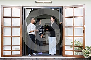 Asian couple looking at house plans and talking with a real estate agent about signing documents for purchase of a new