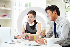 Asian Couple Looking at Laptop Over Breakfast