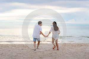 Asian couple in love having romantic tender moments running and hand hold on the beach between sunset in Thailand