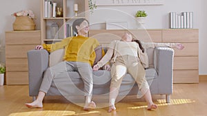 Asian couple love moving sofa or couch into new home jumping on soft sofa relax and rest with happiness feeling together. Cheerful