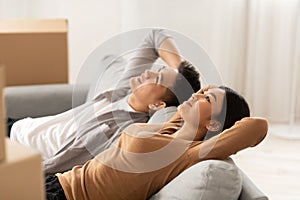 Asian couple lying on new sofa after relocation