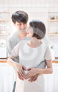 Asian couple making heart shape with their hands on pregnant belly,.Pregnant Woman and Husband holding hands in heart shape on