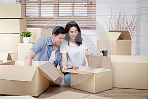 Asian couple moving into a new home Help unpack the brown paper box to decorate the house.