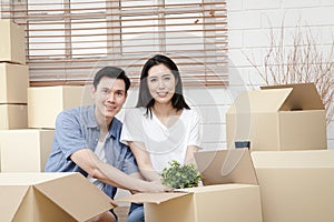 Asian couple moving into a new home Help unpack the brown paper box to decorate the house.