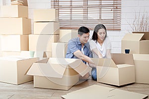 Asian couple moving into a new home Help unpack the brown paper box to decorate the house.