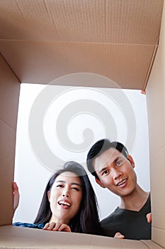 Asian couple moving into a new home Open a large brown cardboard box. Happy smile.