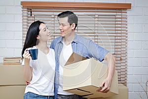 Asian couple moving into a new home There were many large brown cardboard boxes placed in the room.