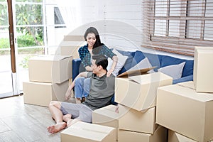 Asian couple moving into a new home There were many large brown cardboard boxes placed in the room.