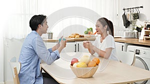 Asian couple newlyweds drink espresso and hot latte in a mug for brunch with nutrition fruit in a wooden bowl when talking about