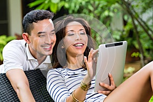 Asian couple outdoor with a tablet pc