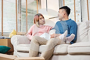 Asian couple planning to decorate house after moving to new home,sitting on sofa with relax emotion