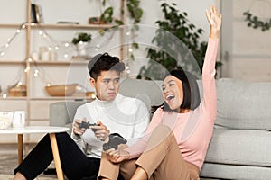 Asian Couple Playing Videogames Together, Girlfriend Winning Game At Home