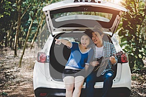 Asian couple pointing and traveling into forest by car, Musician lover. Adventure and outdoors concept. Nature and Lifestyle theme