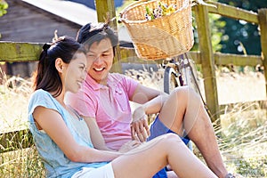 Asian Couple Resting By Fence With Old Fashioned Cycle
