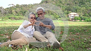 Asian couple senior elder retire relax and watching laptop computer technology