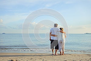 Asian couple senior elder retire resting embrace at sunset beach honeymoon