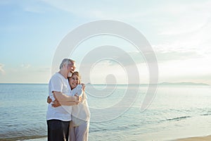 Asian couple senior elder retire resting embrace at sunset beach honeymoon