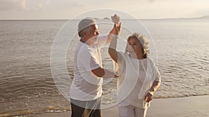 Asian couple senior elder retire resting relax dancing at sunset beach honeymoon family together