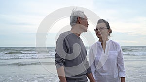 Asian couple senior elder retire resting relax holding hand walking kiss at sunset beach