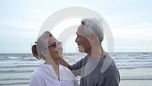 Asian couple senior elder retire resting relax kissing and hugging sunset beach