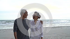 Asian couple senior elder retire resting relax walking at sunset beach honeymoon