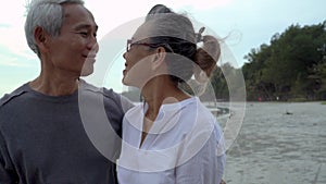 Asian couple senior elder retire resting relax walking at sunset beach honeymoon