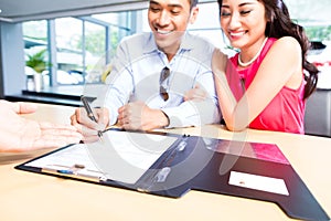 Asian Couple signing sales contract for car