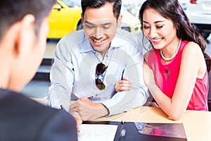 Asian Couple signing sales contract for car