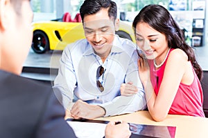 Asian Couple signing sales contract for car