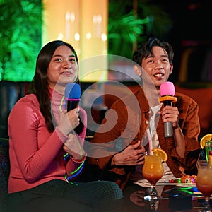 Asian couple singing on a date at karaoke club