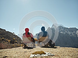 Asian couple sitting in chair on top of mountain looking at view