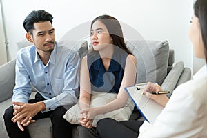 Asian couple sitting on the couch in the room to consult mental health problems by doctor, Health and illness concepts