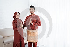 Asian couple smile with gestures of apologize when wish Happy Ramadan Kareem