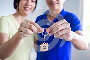 An Asian couple with a smile of happiness holds the key to a new home