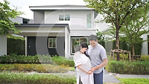 Asian couple standing outside their new house