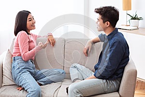 Asian Couple Talking Enjoying Conversation Sitting On Couch At Home