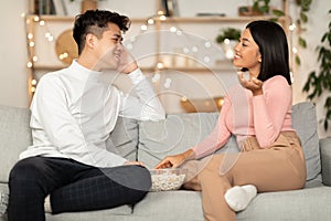 Asian Couple Talking Enjoying Stay-At-Home Date Sitting On Sofa Indoors