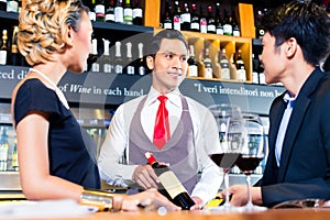 Asian couple tasting red wine in bar