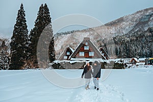 Asian Couple tourist travelling Shirakawago village with white snow, Japan Winter Season