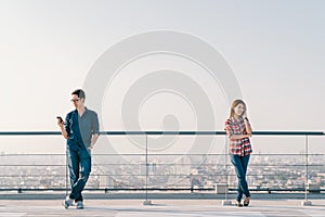 Asian couple using telephone call and smartphone together on building roof. Mobile cellphone device or information technology