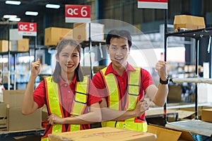 Asian couple warehouse worker smiling and arm raised at counter already preparation container box goods deliverly to customer