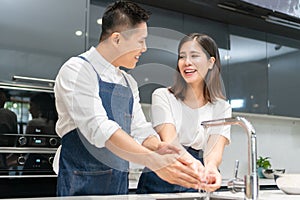 Asian couple washing hands with foam soap before cooking together