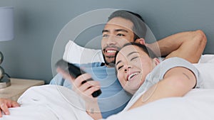Asian couple watching tv in bed at home, happy with funny television subscription service and smile while streaming