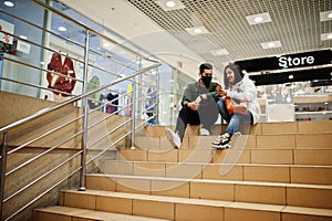 Asian couple wear face mask sitting on stairs at trade center and kooking on smartphone photo