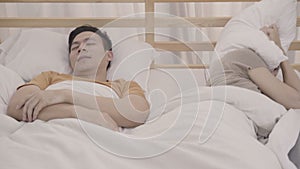 Asian couple wife annoyed Snore`s husband when their sleep in bedroom, couple lying on bed at home female insomnia and can`t sle