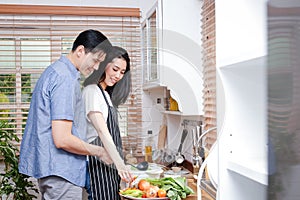 Asian couples cook together in the kitchen at home. They are happy.