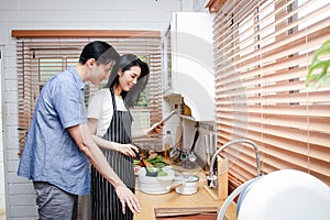 Asian couples cook together in their home kitchens.